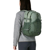 Woman wearing the Patagonia refugio day pack 30L backpack in cover green on her back.