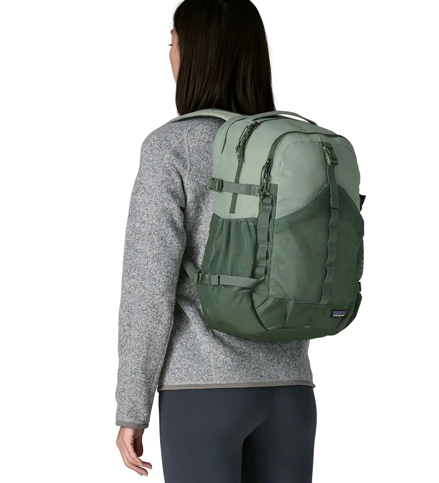 Woman wearing the Patagonia refugio day pack 30L backpack in cover green on her back.