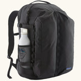 Patagonia refugio day pack 32 litre backpack in black with a white bottle placed in the holder on the side. 