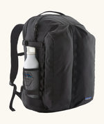 Patagonia refugio day pack 32 litre backpack in black with a white bottle placed in the holder on the side. 