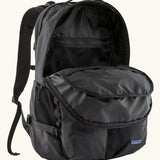 Patagonia refugio day pack 32 litre backpack in black shown with one of the compartments at the front open. 