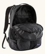Patagonia refugio day pack 32 litre backpack in black shown with one of the compartments at the front open. 