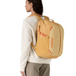 Patagonia yellow 26L day refugio backpack with a buttercup design worn by an adult