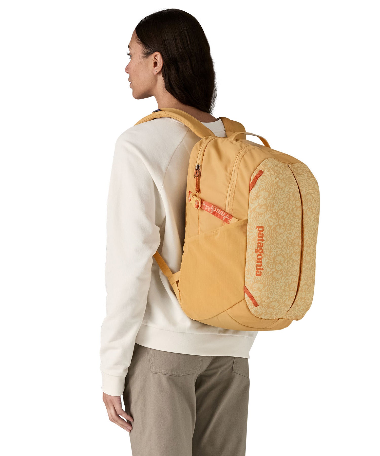 Patagonia yellow 26L day refugio backpack with a buttercup design worn by an adult