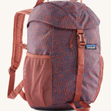 The Patagonia Kids Refugito 12L Backpack   , a dark coral colour backpack with blue patterns all over. Features 2 side mesh pockets and a buckle to close the lid. Logo patch is stitched on the front panel.