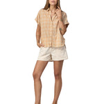 Women wearing a Patagonia Women's A/C Shirt in a pale golden yellow and white check, made from a blend of organic cotton and hemp. She is also wearing white shorts and Birkenstock sandals. 