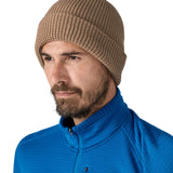 Patagonia adult snow drifter beanie in a pale khaki colour worn by a adult showing the brim turned up.