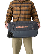 Patagonia 40L black hole wheeled duffel bag being held by an adult
