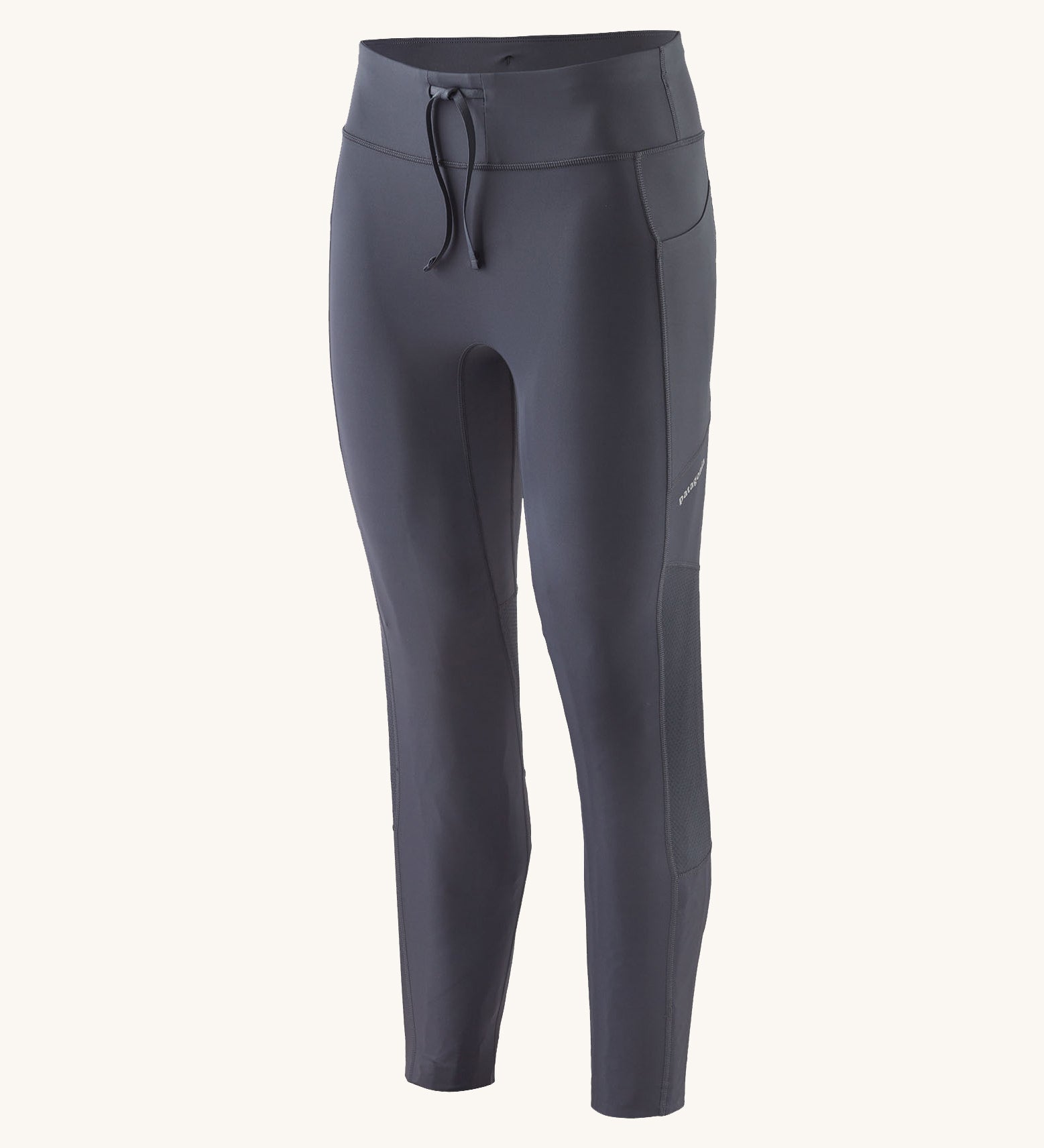 A pair of smolder blue Patagonia running 7/8 tights on a cream background.