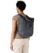 Patagonia Terravia tote bag in smolder blue worn by a adult on the back showing the carrying handle details and side mesh pockets for holding bottles