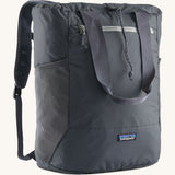 Patagonia Terravia tote bag in smolder blue showing the front zip and strap details with the brand log on the bottom panel. Features shoulder straps for easy carrying.