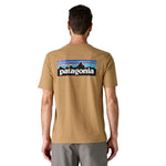 The back of a man wearing the Patagonia men's logo responisbilli tee in talon gold available at Babipur. A short sleeve top in pale yellow with a large brand patch