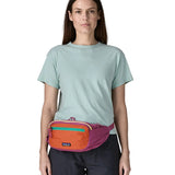 Woman wearing Patagonia's terravia hip pack in bright purple with an orange front panel around the waist