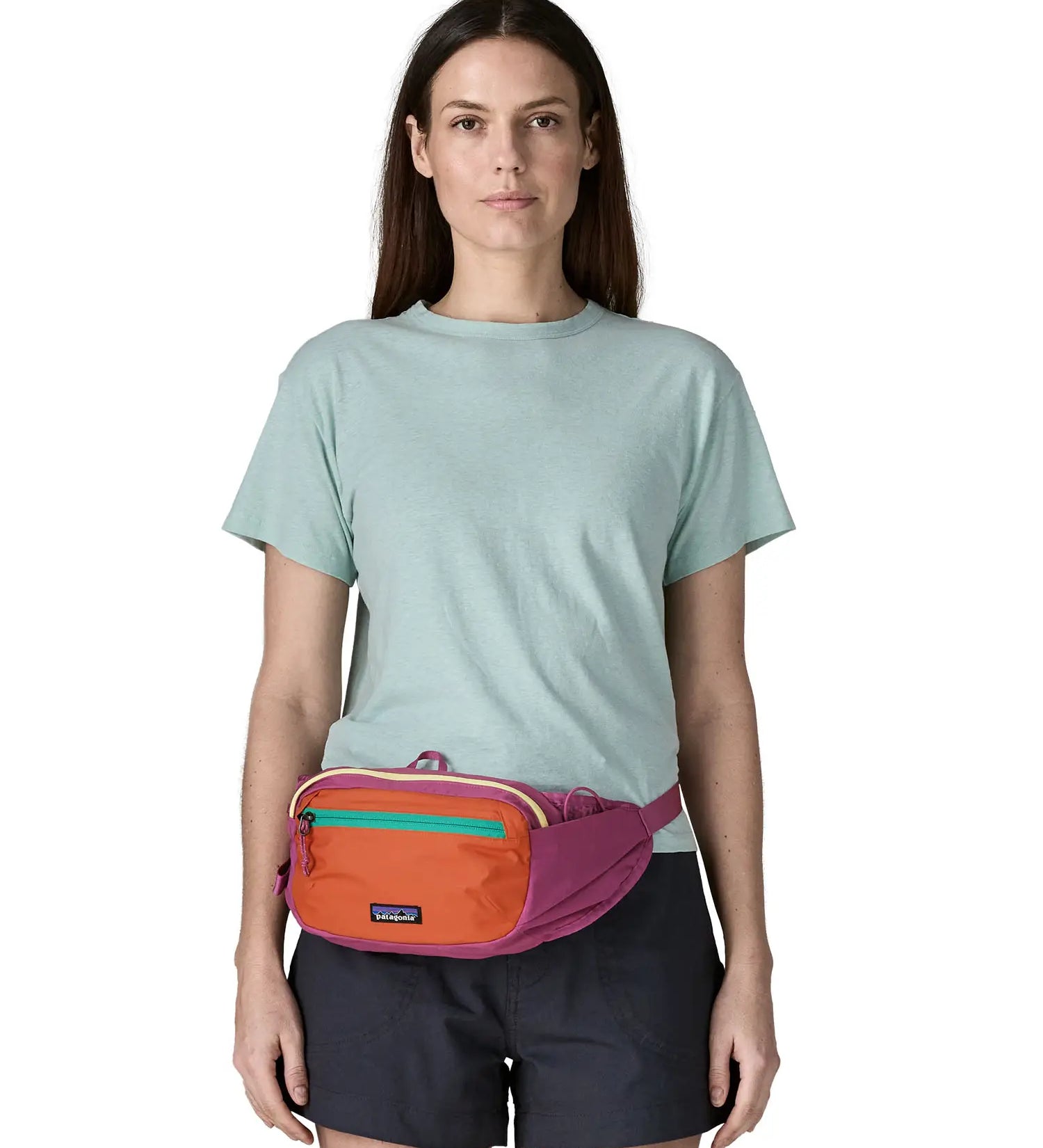 Woman wearing Patagonia's terravia hip pack in bright purple with an orange front panel around the waist
