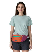 Woman wearing Patagonia's terravia hip pack in bright purple with an orange front panel around the waist