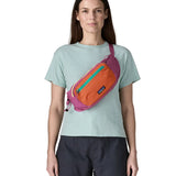 Woman wearing Patagonia's terravia hip pack in bright purple with an orange front panel over the shoulder