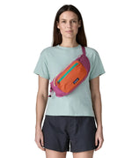 Woman wearing Patagonia's terravia hip pack in bright purple with an orange front panel over the shoulder