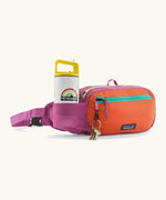 Patagonia terravia hip pack in bright purple with an orange front panel showing bottle inside the mesh pocket and pocket hanging from loop