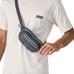 A close up of a man wearing the Patagonia Terravia Mini Bum Bag Hip Pack in a Smolder Blue colour on his shoulder, across his chest. 