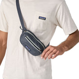 A close up of a man wearing the Patagonia Terravia Mini Bum Bag Hip Pack in a Smolder Blue colour on his shoulder, across his chest. 