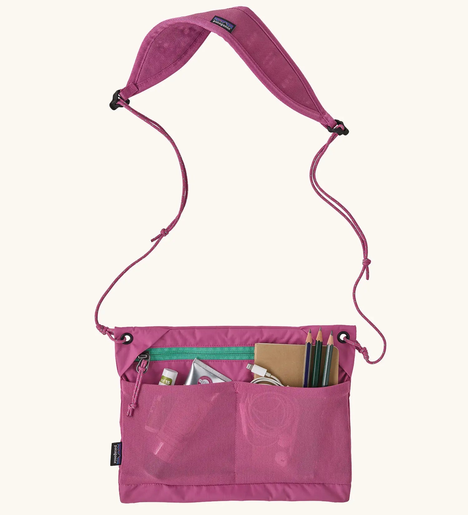 Patagonia terravia sacoche cross body bag in bright purple showing various items in front mesh pockets