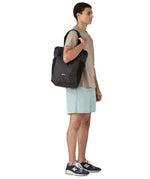 Patagonia Terravia tote bag in black carried by a adult on the shoulder showing the side pockets for holding bottles