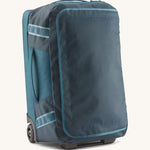 Patagonia 40L wheeled duffel bag in a tidal teal colour on a cream backgroud.