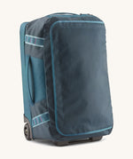 Patagonia 40L wheeled duffel bag in a tidal teal colour on a cream backgroud.