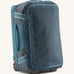 Patagonia 40L wheeled duffel bag in a tidal teal colour on a cream backgroud.
