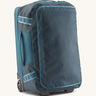 Patagonia 40L wheeled duffel bag in a tidal teal colour on a cream backgroud.