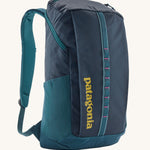 Patagonia 25L black hole backpack in a tidal teal colour on a cream background.