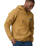 A man wearing a Patagonia Unity Fitz Uprisal Hoody in a yellow colour stood in front of a plain background.