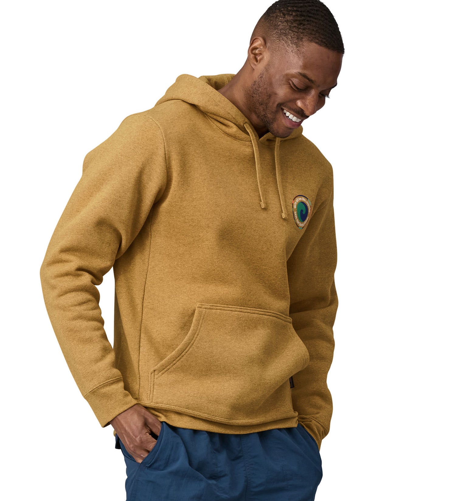 A man wearing a Patagonia Unity Fitz Uprisal Hoody in a yellow colour stood in front of a plain background.