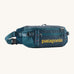 Patagonia 5L waist pack in a tidal teal colour on a cream background