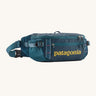 Patagonia 5L waist pack in a tidal teal colour on a cream background
