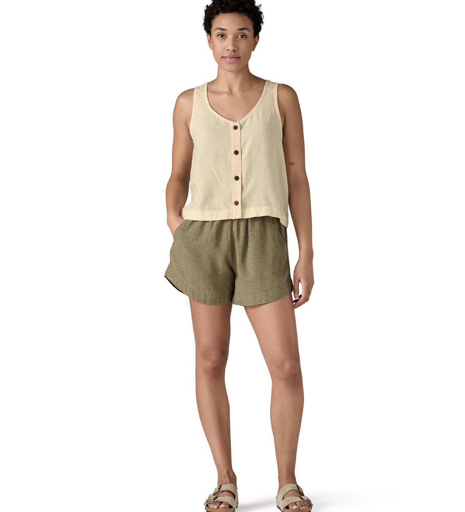 Woman wearing a Patagonia women's sleeveless garden island top in light cream with the button up closure on the front.