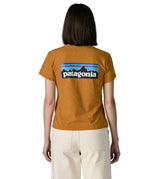 Woman wearing the Patagonia women's P-6 logo responsibili-tee short sleeved t-shirt in dried mango yellow showing the large logo on the back. 