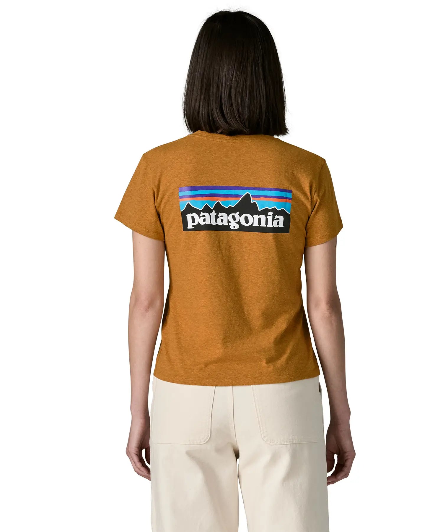 Woman wearing the Patagonia women's P-6 logo responsibili-tee short sleeved t-shirt in dried mango yellow showing the large logo on the back. 