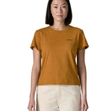 Woman wearing the Patagonia women's P-6 logo responsibili-tee short sleeved t-shirt in dried mango yellow with small logo on the chest.