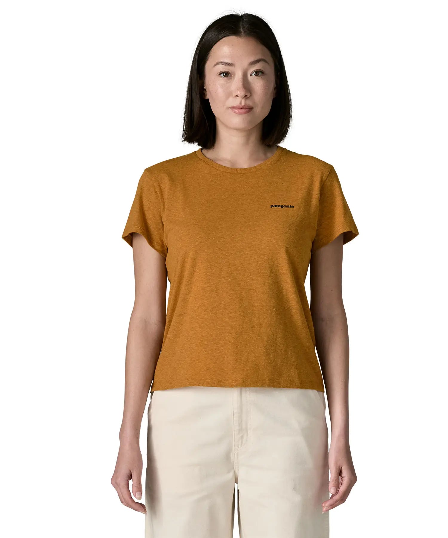 Woman wearing the Patagonia women's P-6 logo responsibili-tee short sleeved t-shirt in dried mango yellow with small logo on the chest.