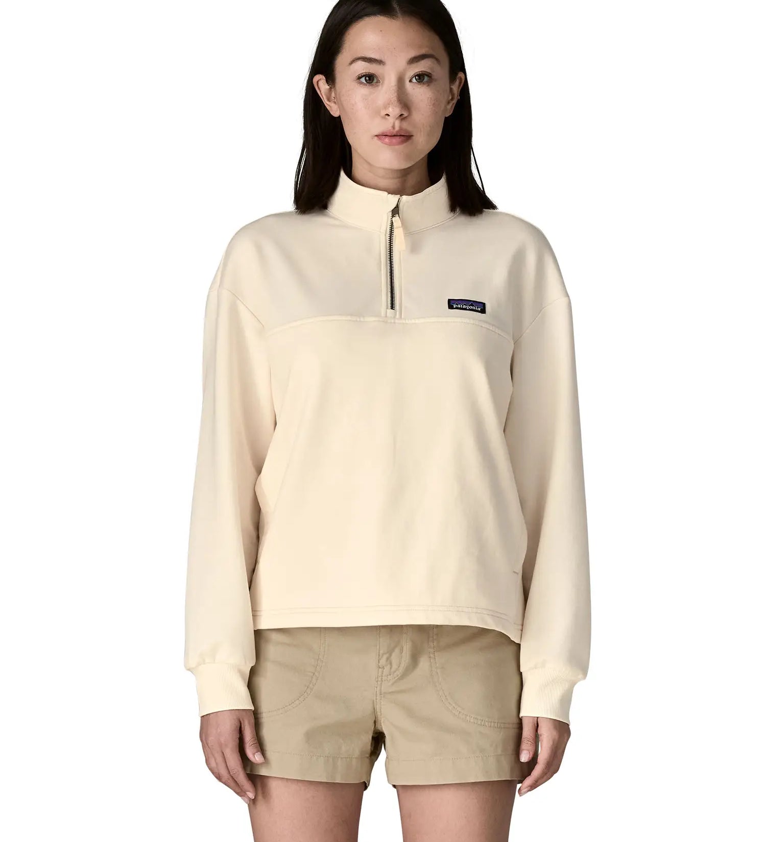 A woman wearing a cream Patagonia Women's Ahnya Pullover showing 1/4 length front zip.