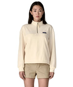 A woman wearing a cream Patagonia Women's Ahnya Pullover showing 1/4 length front zip.