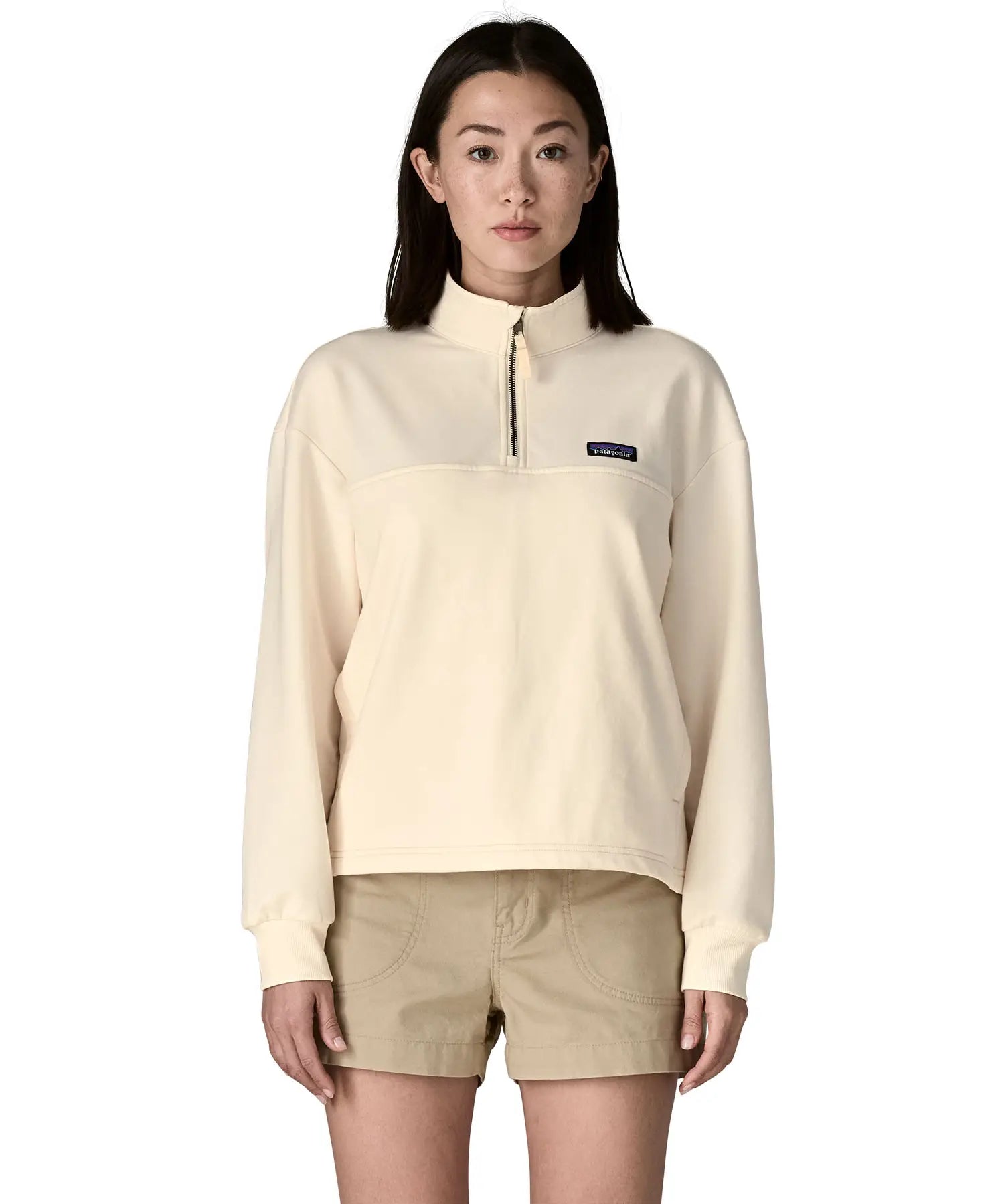 A woman wearing a cream Patagonia Women's Ahnya Pullover showing 1/4 length front zip.