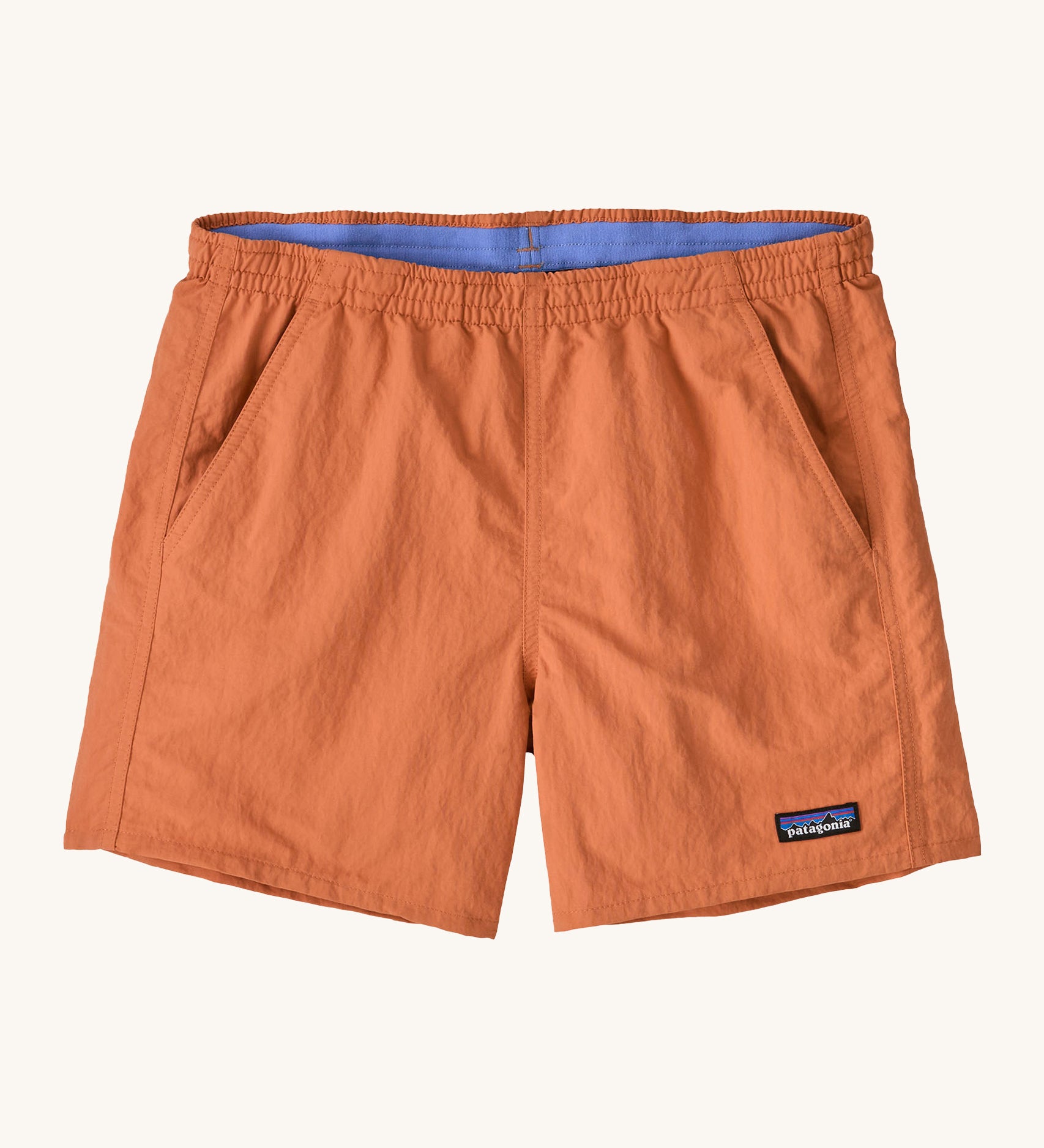 Patagonia women's baggies short in a light orange colour on a cream background.