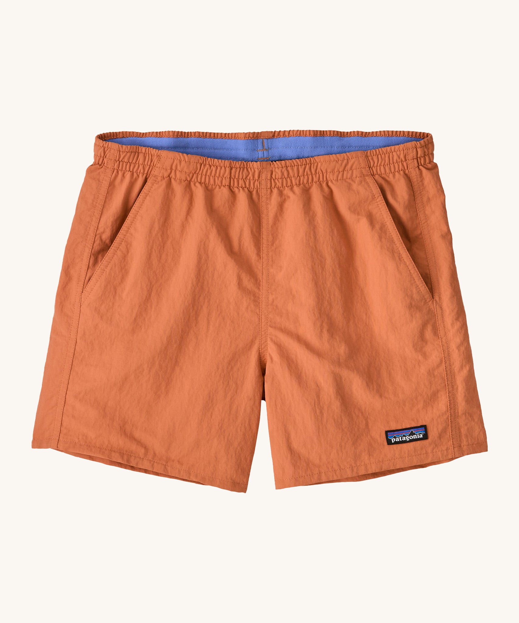 Patagonia women's baggies short in a light orange colour on a cream background.