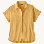 The Patagonia Women's A/C Shirt in a pale golden yellow, made from a blend of organic cotton and hemp. It has a relaxed, boxy fit, and features rolled sleeves, full lenght buttons and a droptail hem. 