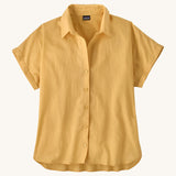 The Patagonia Women's A/C Shirt in a pale golden yellow, made from a blend of organic cotton and hemp. It has a relaxed, boxy fit, and features rolled sleeves, full lenght buttons and a droptail hem. 