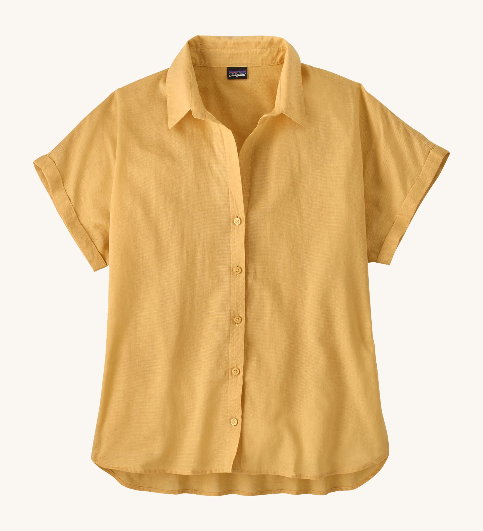 The Patagonia Women's A/C Shirt in a pale golden yellow, made from a blend of organic cotton and hemp. It has a relaxed, boxy fit, and features rolled sleeves, full lenght buttons and a droptail hem. 
