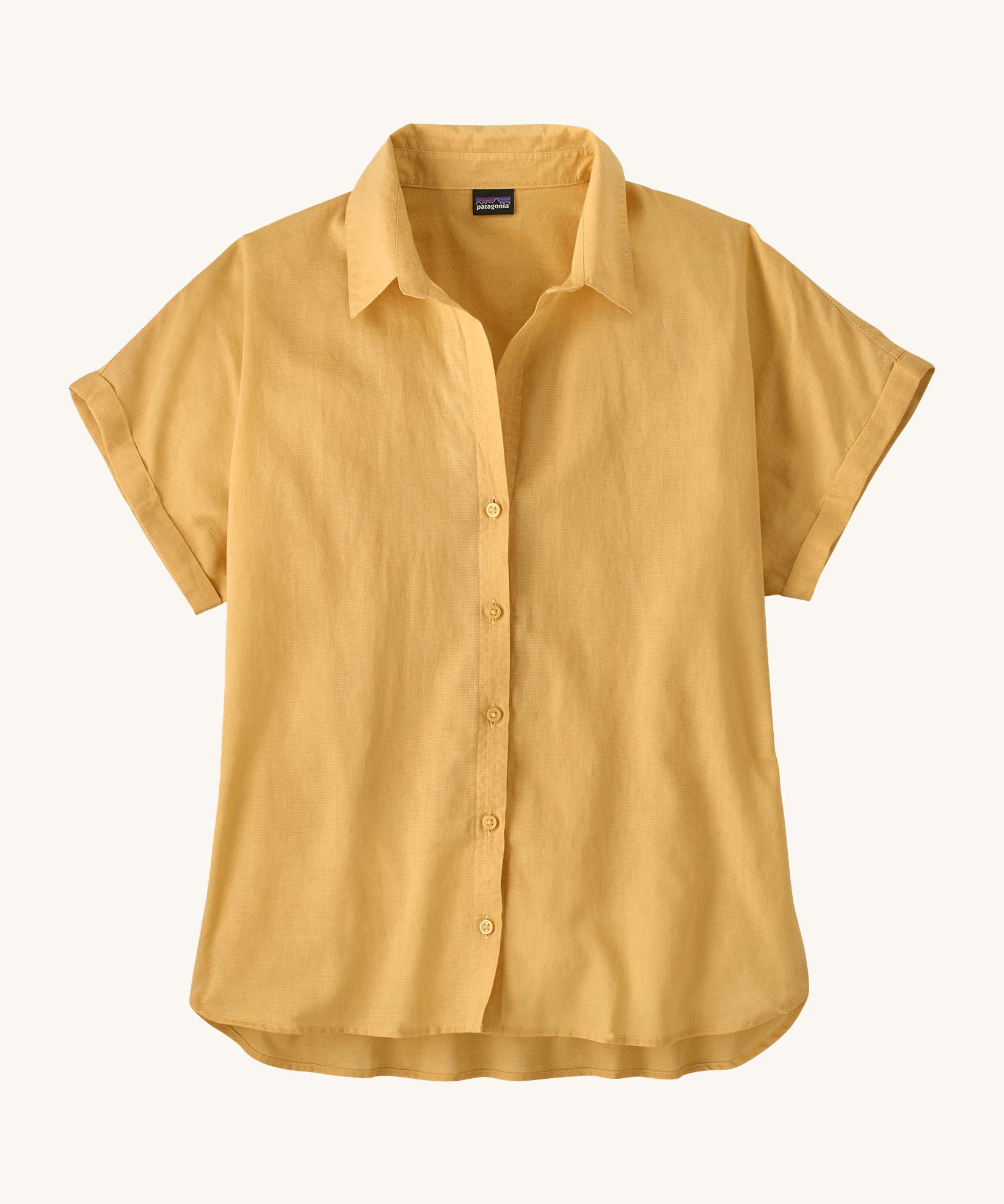 The Patagonia Women's A/C Shirt in a pale golden yellow, made from a blend of organic cotton and hemp. It has a relaxed, boxy fit, and features rolled sleeves, full lenght buttons and a droptail hem. 