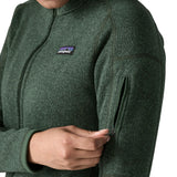 Woman wearing the Patagonia women’s better sweater fleece jacket in green. Close up of zipped arm pocket being unzipped.